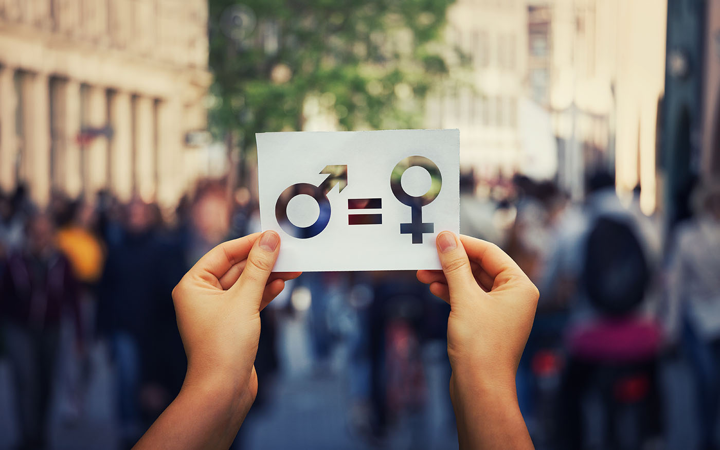 Deux mains tenant une pancarte représentant l'égalité entre les femmes et les hommes